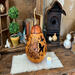 A decorative gourd light or vase. The front has s hand drawn cat enjoying a butterfly garden. Two butterfly shapes are carved into the shell